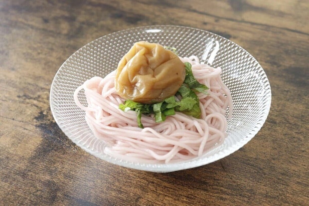 円錐形のガラス鉢に盛り付けられたピンク色の麺と梅干し