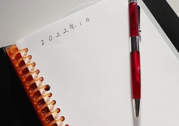 ノートに「2022年1月」と書かれ、赤いペンが置かれている ノートに「2022年1月」と書かれ、赤いペンが置かれている