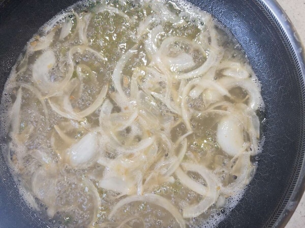 フライパンで薄切り玉ねぎとみじん切りにんにくがバターで炒められている様子 フライパンで薄切り玉ねぎとみじん切りにんにくがバターで炒められている様子