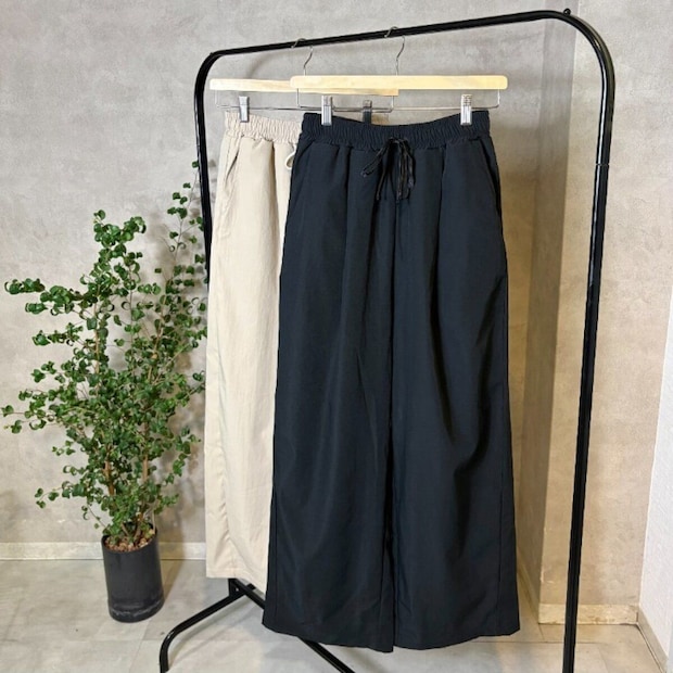 ハンガーラックに掛かるベージュと黒のワイドパンツ ハンガーラックに掛かるベージュと黒のワイドパンツ
