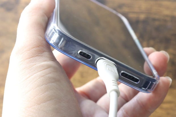 ケースを装着したiPhoneに充電ケーブルを接続している