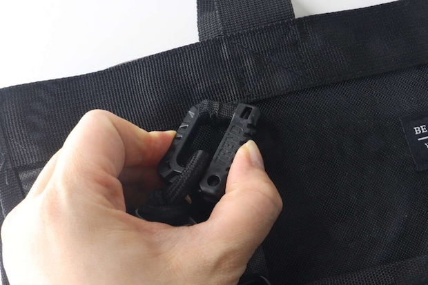 女性の指がバッグに取り付けられたキーホルダーの開閉部分を操作している様子 女性の指がバッグに取り付けられたキーホルダーの開閉部分を操作している様子