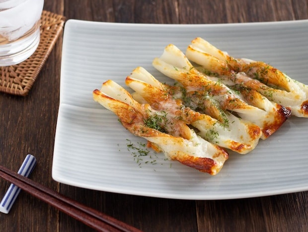 ねじったちくわにチーズと青のりをのせて焼いたものが白い皿に4本並んでいる ねじったちくわにチーズと青のりをのせて焼いたものが白い皿に4本並んでいる