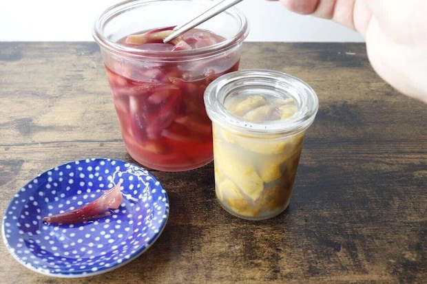 青い豆皿に赤い漬物、奥に瓶詰めの漬物が並ぶ