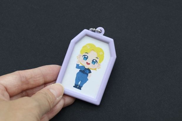 完成したお守り型キーホルダーを手に持ち、裏面のイラストを見せている 完成したお守り型キーホルダーを手に持ち、裏面のイラストを見せている