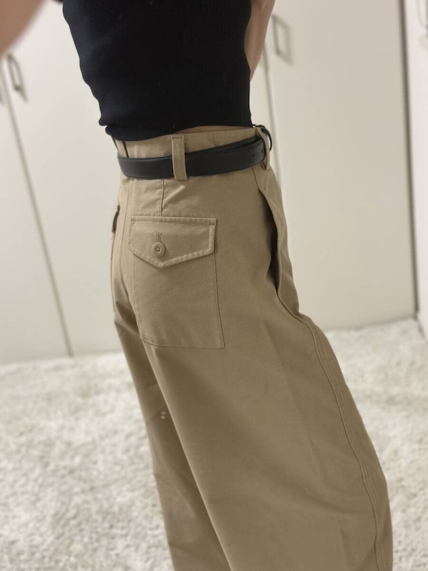 黒トップスとベージュパンツを着用した女性の後ろ姿