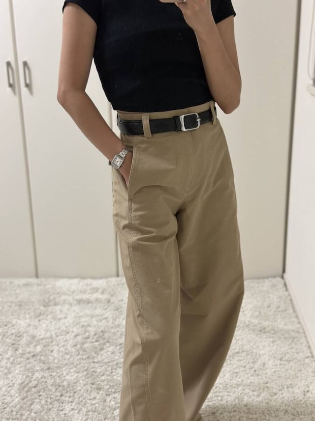 黒トップスとベージュパンツの女性がポケットに手を入れている