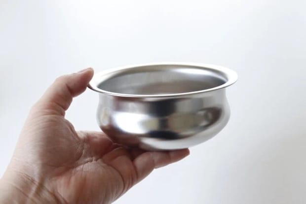 女性の手で持たれた丸みのあるステンレス製カレーポット 女性の手で持たれた丸みのあるステンレス製カレーポット