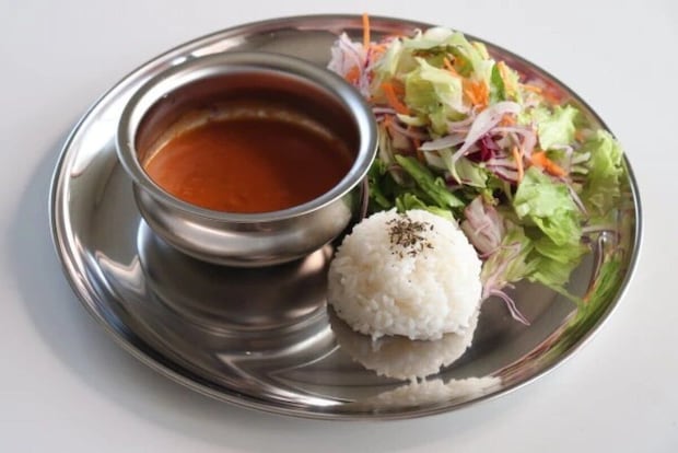 ステンレス皿にカレーポット、ライス、サラダが盛り付けられた様子