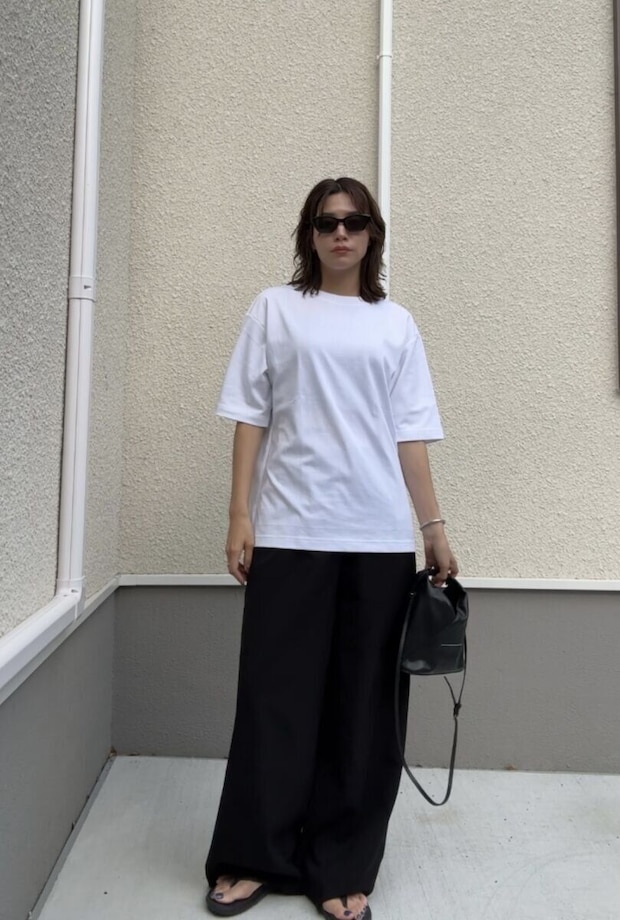 白いTシャツと黒いワイドパンツを着用し、サングラスをかけた女性がバッグを持って立っている 白いTシャツと黒いワイドパンツを着用し、サングラスをかけた女性がバッグを持って立っている