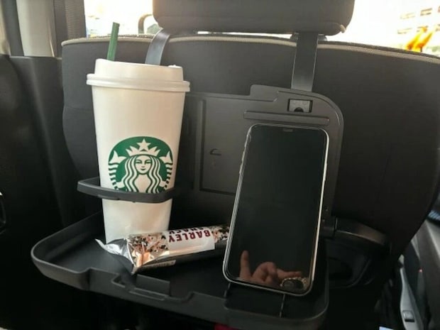 後部座席のリアシートトレイに飲み物とお菓子、スマホが置かれている