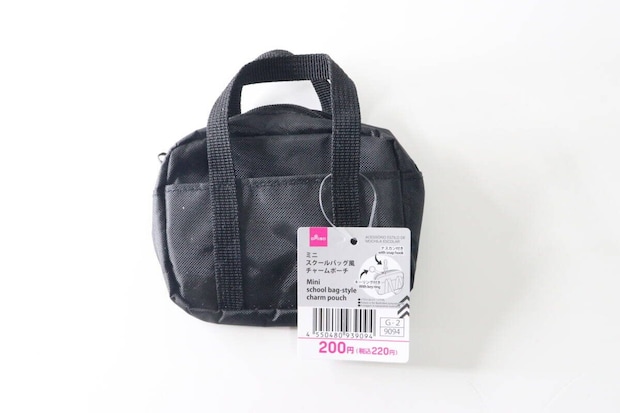 黒いミニスクールバッグ風チャームポーチが商品タグ付きで置かれている