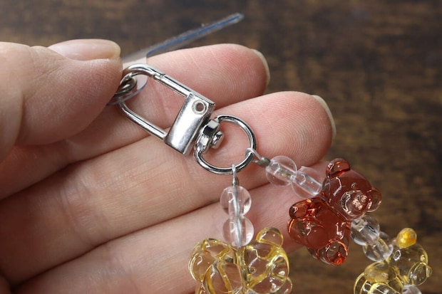 指でつまんだスマホストラップの回転式カラビナ金具