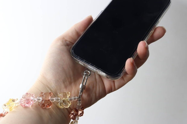 女性がスマホを手に持ちストラップを手首に通している様子 女性がスマホを手に持ちストラップを手首に通している様子