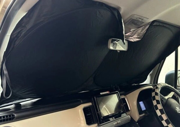 車のフロントガラスに設置され日差しを防いでいる黒いサンシェード 車のフロントガラスに設置され日差しを防いでいる黒いサンシェード