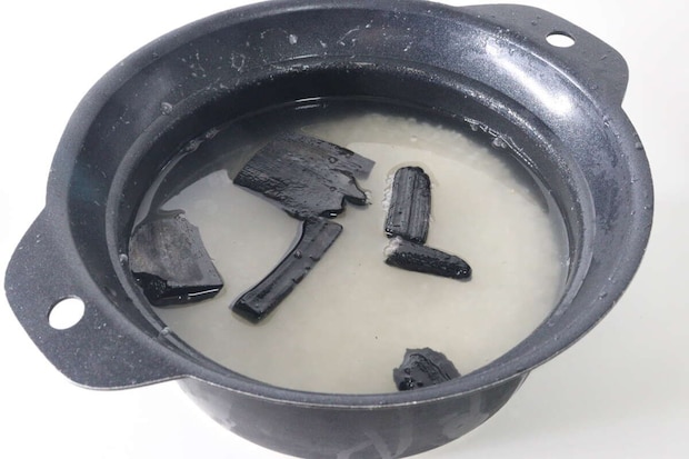 炊飯器の釜に米と水、そして竹炭が数個入っている様子 炊飯器の釜に米と水、そして竹炭が数個入っている様子