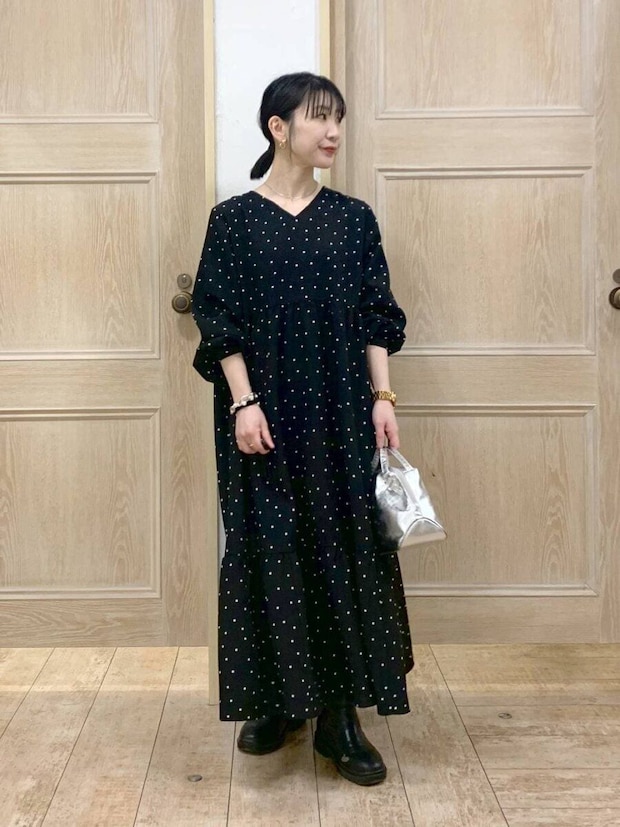 黒のドット柄ワンピースを着てシルバーバッグを持つ女性 黒のドット柄ワンピースを着てシルバーバッグを持つ女性
