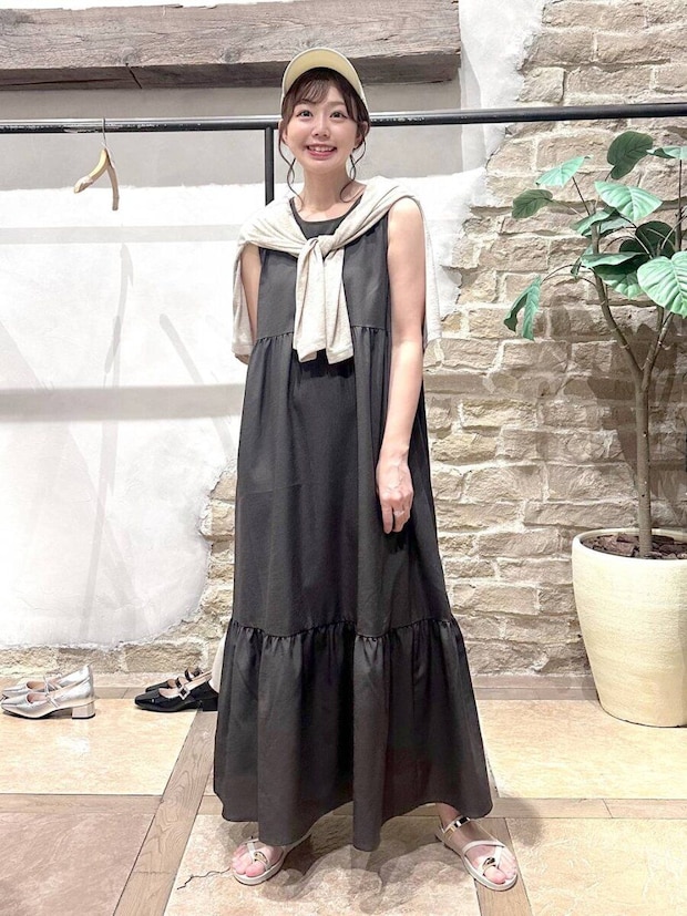 黒ノースリーブワンピにベージュカーデを羽織った女性