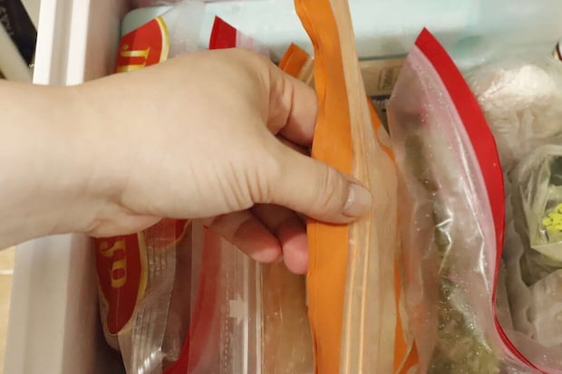 冷凍庫から立てて収納された冷凍食品を、手がスムーズに取り出している様子