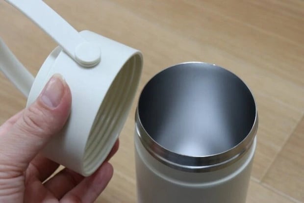 白いペットボトルホルダーの蓋を片手で開けている 白いペットボトルホルダーの蓋を片手で開けている