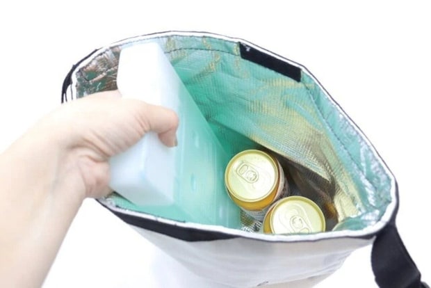 クーラーバッグに緑色の保冷剤と缶飲料を入れている クーラーバッグに緑色の保冷剤と缶飲料を入れている