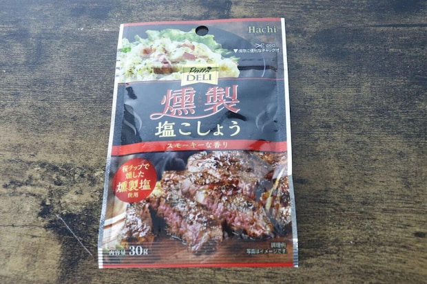 「PattoDELI 燻製塩こしょう」の黒いパッケージが木目のテーブルに置かれている