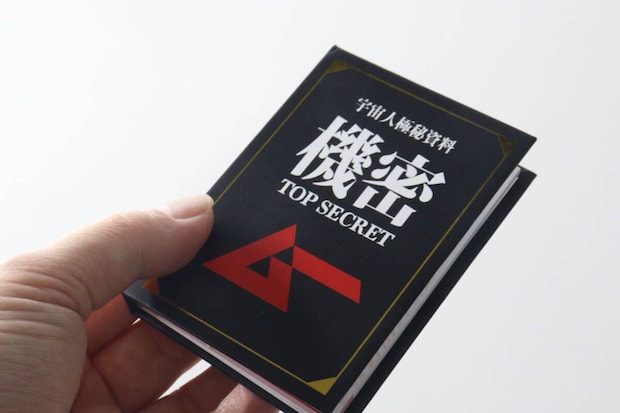 手に持った「宇宙人極秘資料 機密 TOP SECRET」と書かれた黒いブック型メモ帳 手に持った「宇宙人極秘資料 機密 TOP SECRET」と書かれた黒いブック型メモ帳