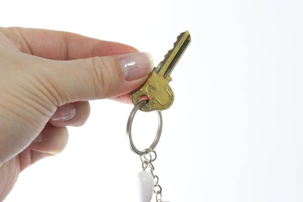 女性がキーホルダーのリングに鍵を取り付けている