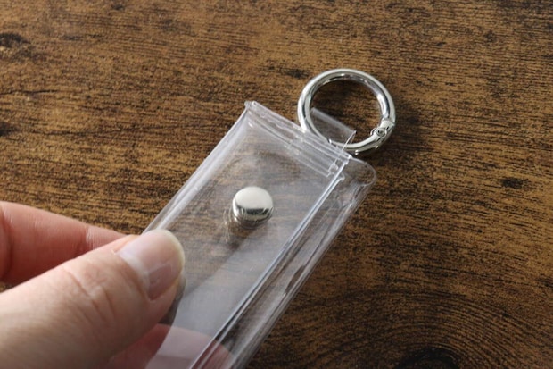 手がPVCコインポーチの留め具部分をつまんで開けようとしている 手がPVCコインポーチの留め具部分をつまんで開けようとしている