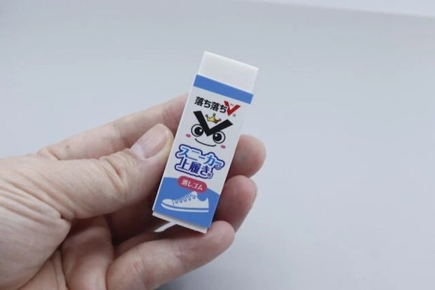 「落ち落ちV」と書かれたスニーカー&上履き用消しゴムを女性が指でつまんで持っている 「落ち落ちV」と書かれたスニーカー&上履き用消しゴムを女性が指でつまんで持っている