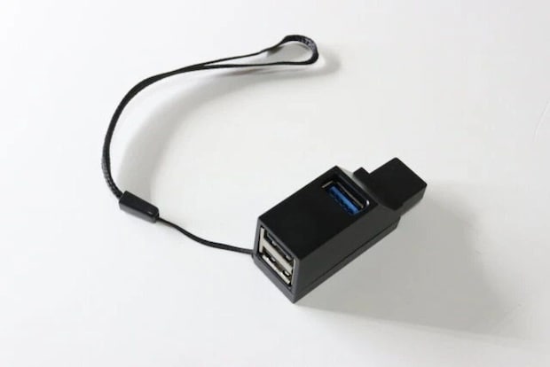黒いUSBハブとストラップが白い背景に置かれている 黒いUSBハブとストラップが白い背景に置かれている