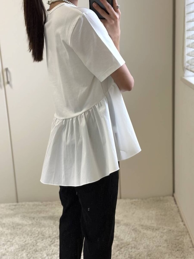 白いペプラムTシャツと黒パンツを着た女性の横向き 白いペプラムTシャツと黒パンツを着た女性の横向き