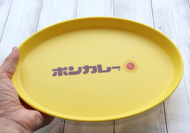 手で黄色いボンカレー皿を持っている様子。皿のサイズ感がわかる