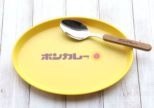 黄色いボンカレー皿にスプーンが置かれているアップ。木目調の柄にボンカレーロゴ 黄色いボンカレー皿にスプーンが置かれているアップ。木目調の柄にボンカレーロゴ