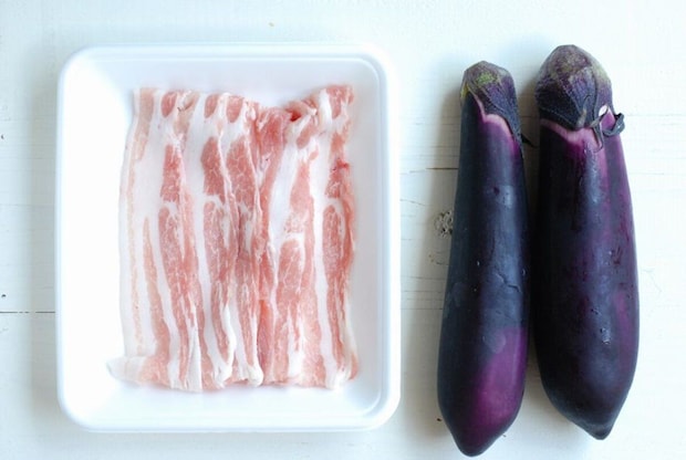 白いトレーに入った豚バラ肉と、隣に並べられた2本のなす 白いトレーに入った豚バラ肉と、隣に並べられた2本のなす