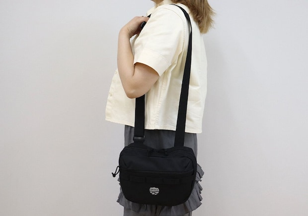 黒いショルダーバッグを肩掛けした女性の全身