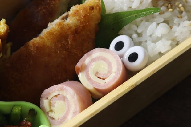 お弁当のハムロールにぎょろ目ピックスが刺さっている