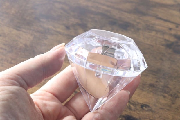 女性の手がダイヤモンド型クリアケースの蓋を開けている