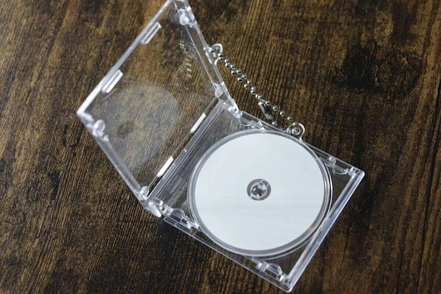 透明なCDケース型キーホルダーが開いており、中に白いCDが見える 透明なCDケース型キーホルダーが開いており、中に白いCDが見える