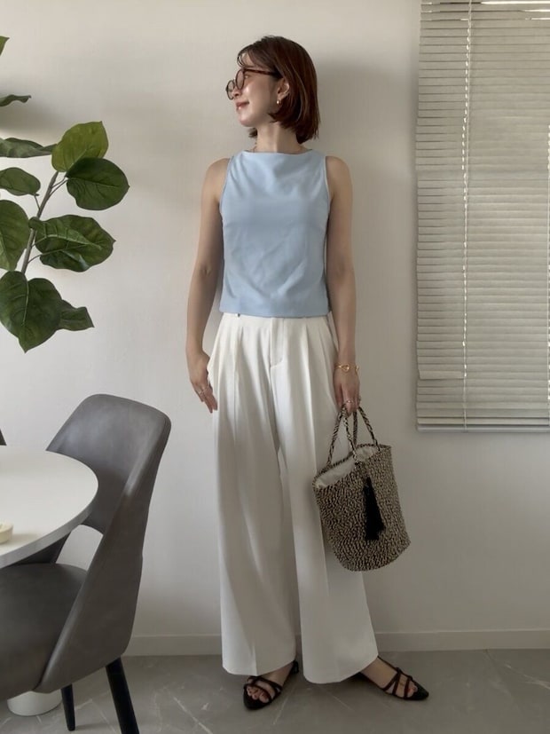 白いパンツに水色のノースリーブトップスを合わせた女性の夏コーデ、かごバッグ