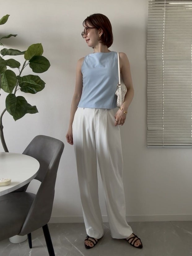 白いパンツに水色のノースリーブトップスを合わせた女性の夏コーデ、白いミニバッグ