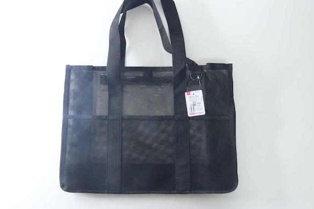 白い背景に置かれた黒いメッシュ素材のトートバッグ。商品タグが付いている。 白い背景に置かれた黒いメッシュ素材のトートバッグ。商品タグが付いている。