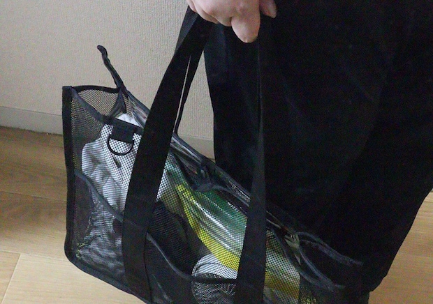 黒い服を着た人物がメッシュバッグを肩に掛けて持ち運んでいる様子。 黒い服を着た人物がメッシュバッグを肩に掛けて持ち運んでいる様子。