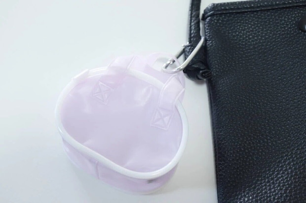 紫色のPVCミニスクールバッグが黒いバッグにカラビナで付いている 紫色のPVCミニスクールバッグが黒いバッグにカラビナで付いている