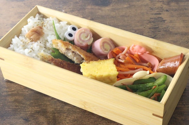 木製のお弁当箱に、おかずカップに入ったおかずが彩り豊かに詰められている 木製のお弁当箱に、おかずカップに入ったおかずが彩り豊かに詰められている