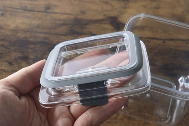 女性の手が密閉容器のフタを裏返しに持ち、グレーのパッキンが付いているのが見える