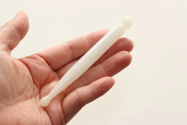 女性の手のひらに白いほぐしスティックが乗せられている