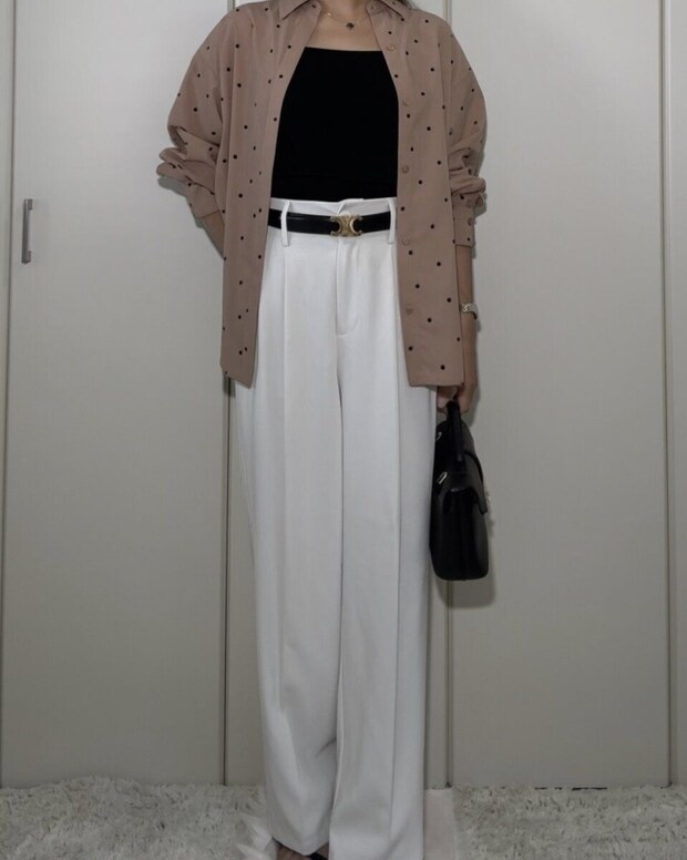 黒いニットインナーと白いワイドパンツにベージュのドット柄シャツを羽織る女性