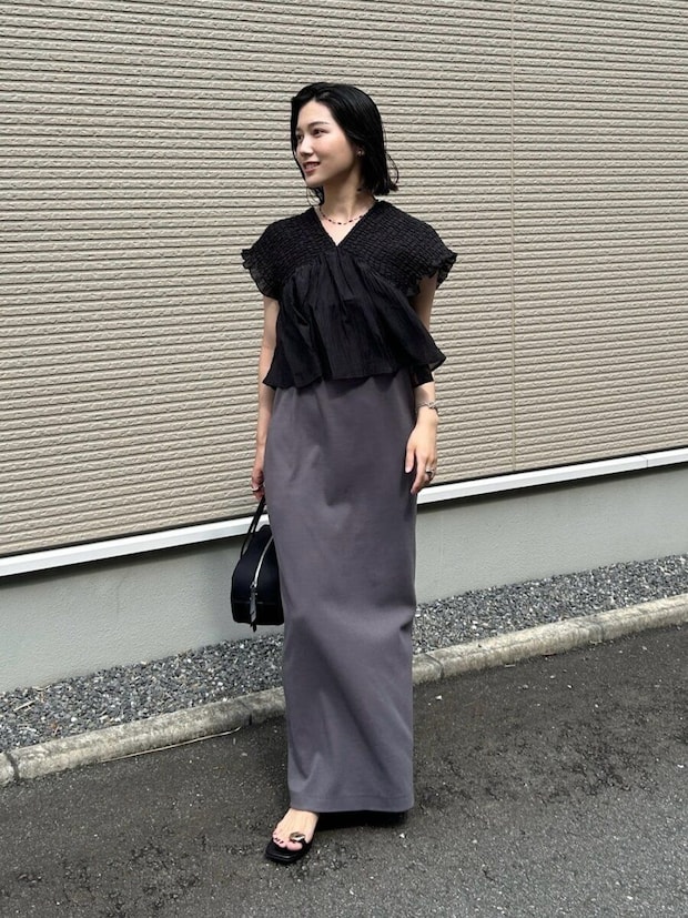 黒ブラウスとグレーのキャミワンピースを重ね着した女性の全身