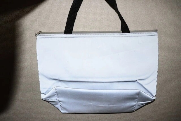 暗い場所で光を反射して輝くグレーの保冷トートバッグ。 暗い場所で光を反射して輝くグレーの保冷トートバッグ。